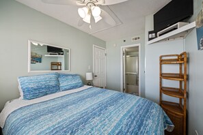 A bedroom with a bed, a ceiling fan, a TV, and a wardrobe.