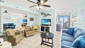 A living room with a ceiling fan, a television, a sofa, and a dining table.