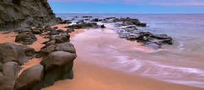 Ein Strand mit großen Felsen und einer Klippe.