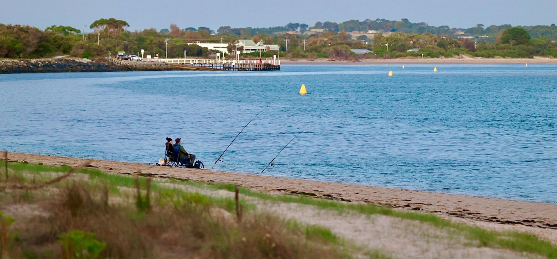 A beach with a pier and a boat docked in the background.
