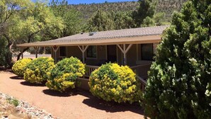Eine Lodge mit überdachter Veranda, umgeben von gepflegten Büschen und Bäumen.