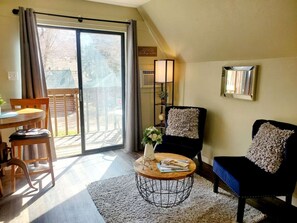 Un salon comprenant un coin repas, un canapé, une table basse et une porte-fenêtre coulissante donnant sur une terrasse extérieure.
