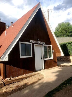 Un piccolo edificio in legno con tetto rosso, un'insegna con la scritta 'Branding Iron' e una porta con una finestra.