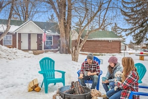 A cabin with a fireplace, outdoor seating, and a snow-covered yard. - Cabin 14: Cute Rustic A-Frame Cozy Getaway w/ Kitchen (Glenwood Springs)