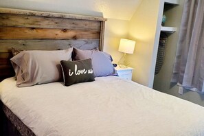 A bed with a wooden headboard, a bedside lamp, and a pillow with text. - Cabin 14: Cute Rustic A-Frame Cozy Getaway w/ Kitchen (Glenwood Springs)