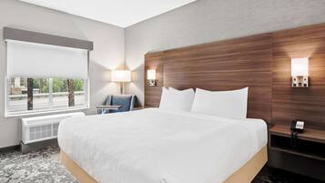 Habitación de hotel con una cama grande, un escritorio, una silla, un ventanal con vistas y un teléfono en la mesita de noche.