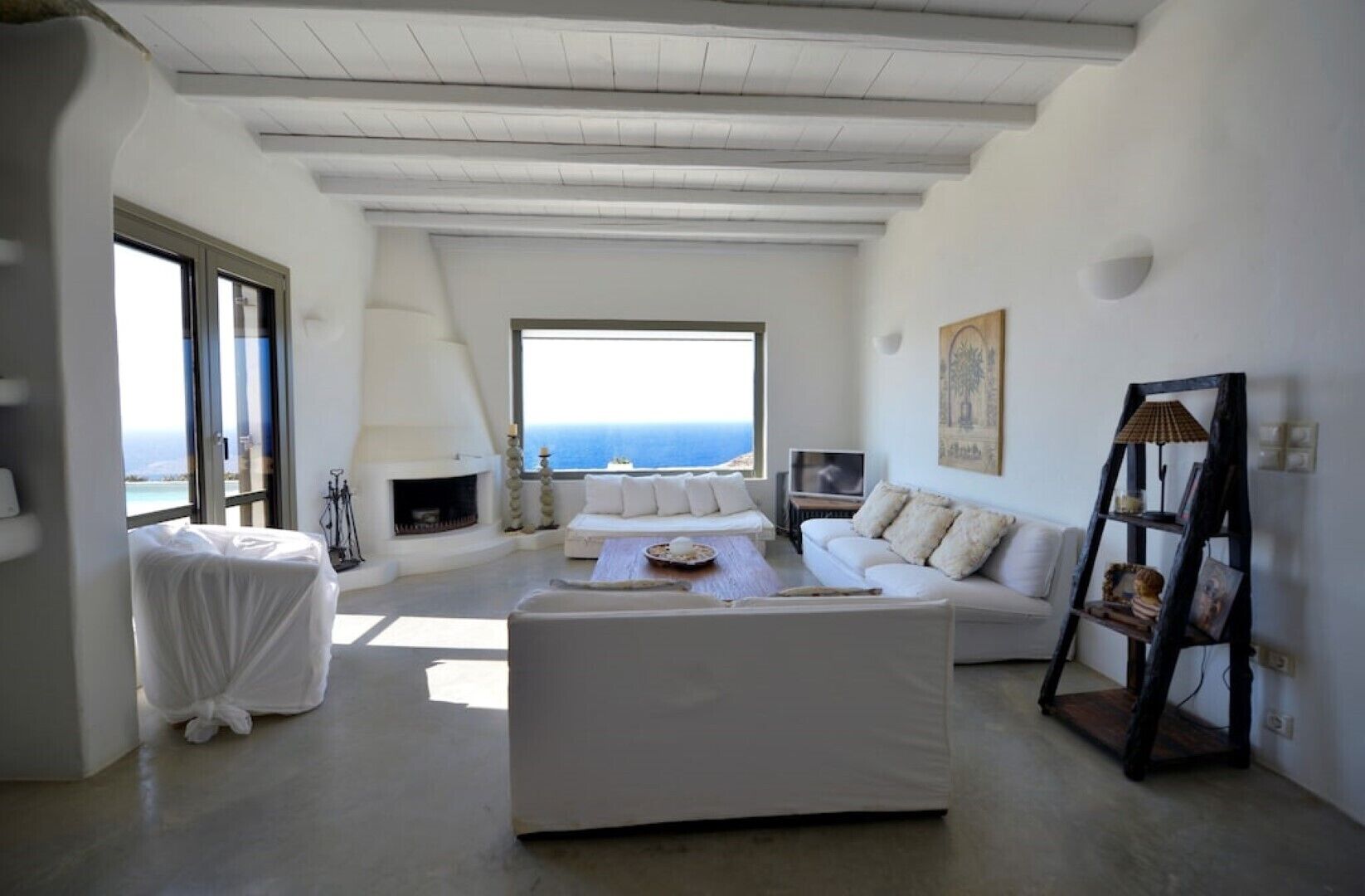 Amplia sala de estar con un gran ventanal que ofrece vistas al mar, una chimenea y un rincón de descanso acogedor.