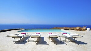 A poolside area with lounge chairs and a view of the sea. - 5 Bedroom Spectacular sunset view villa (Coressia)