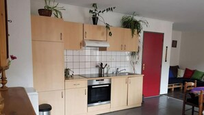 A modern kitchen with light wooden cabinets, a stainless steel oven, and a tiled backsplash. - Petit Appartement Lumineux et Indépendant (Lalaye)