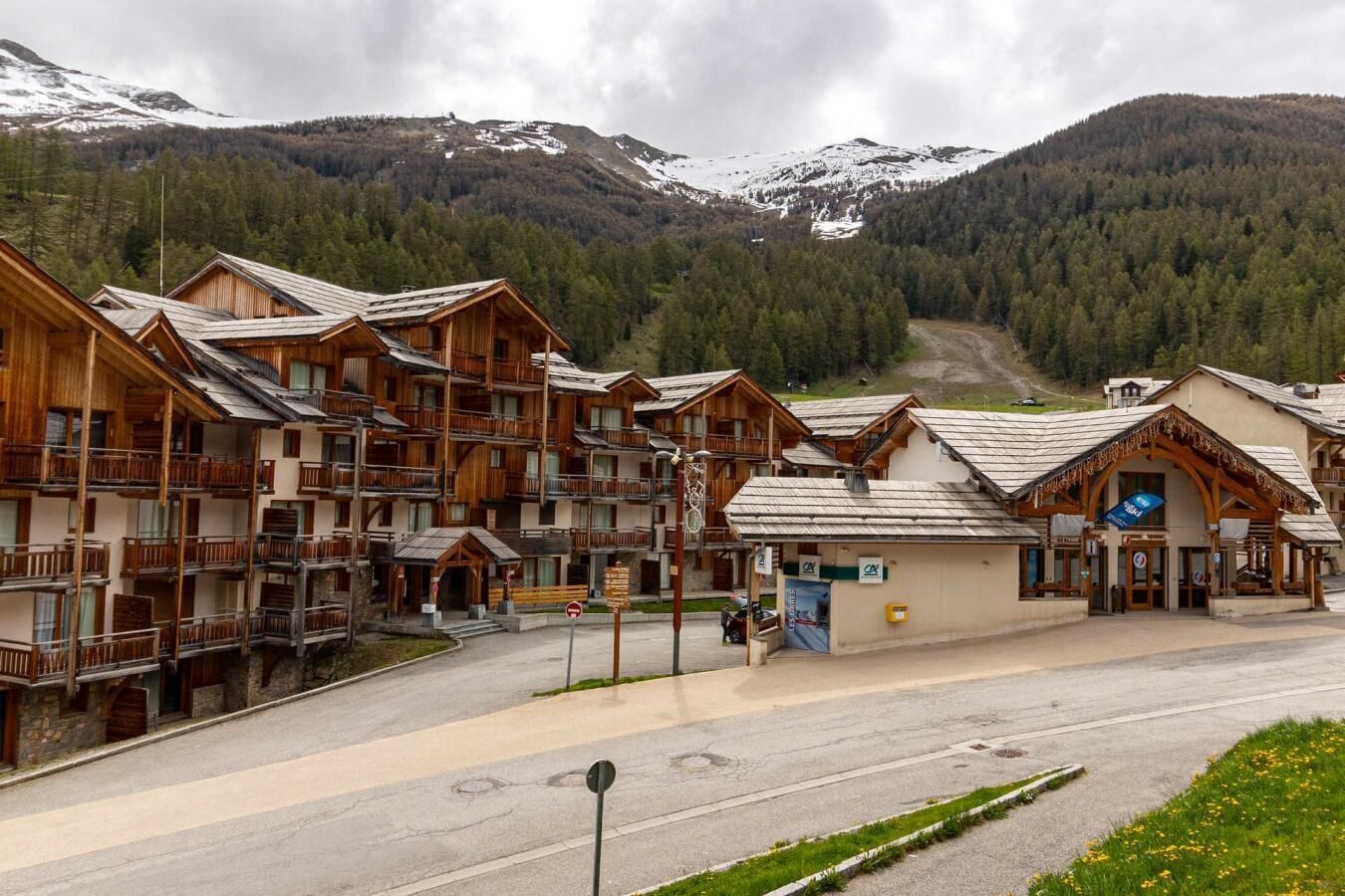 A wooden lodge with multiple balconies and a ski lift in the background.