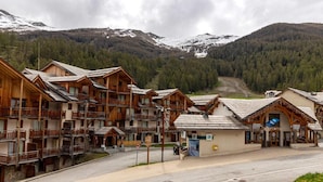 A wooden lodge with multiple balconies and a ski lift in the background. - 150m from ski slopes, 4th floor, view resort, swimming pool, sauna, balcony, ski locker, 33m² (Les Orres)