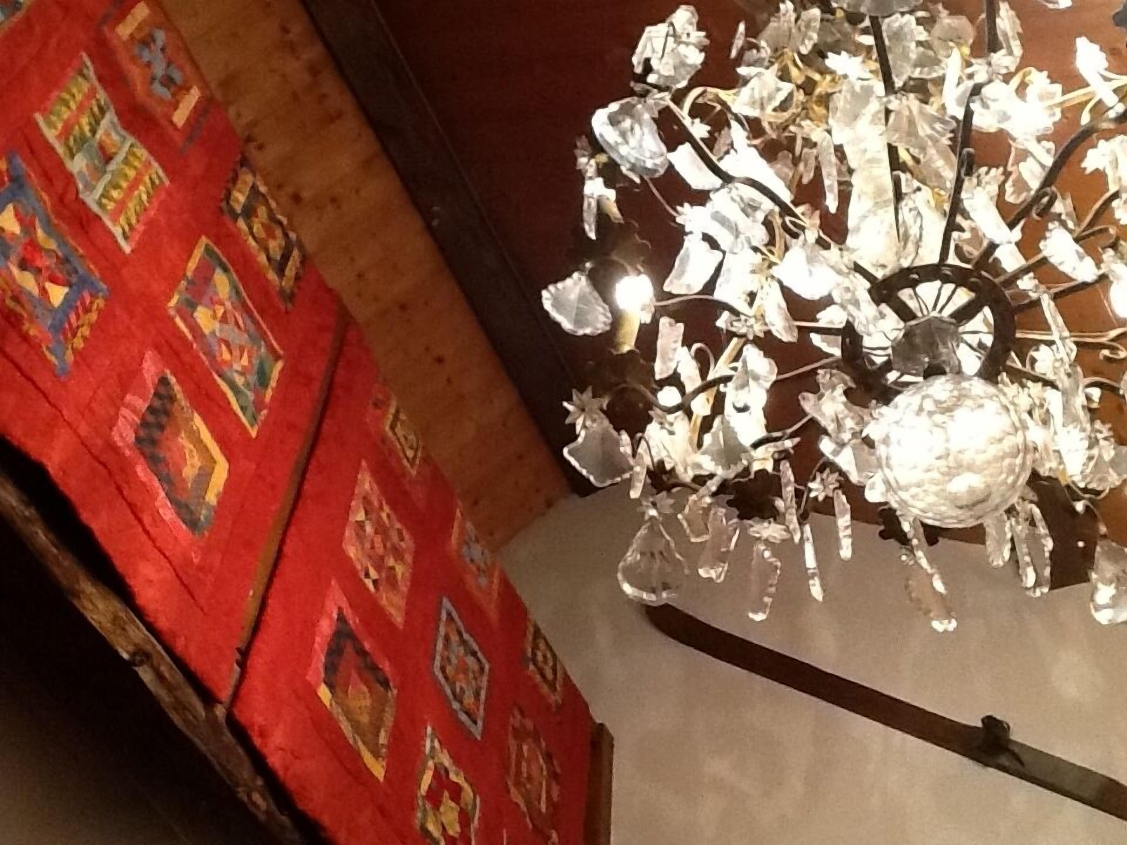 A chandelier with crystal elements and a red patterned wall.