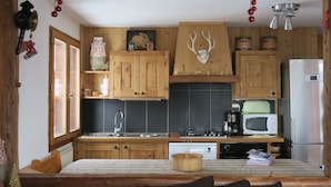 A rustic kitchen with wooden cabinets, a microwave, a refrigerator, and a sink. - Beautiful apartment in a chalet, shared sauna at the foot of the slopes (Valmorel)