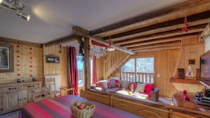 A cozy log cabin room with a large bed, a wooden bench, and a dining table. - Beautiful apartment in a chalet, shared sauna at the foot of the slopes (Valmorel)