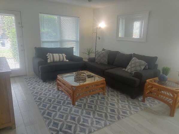 A living room with two sofas, a glass coffee table, and a floor lamp.
