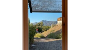 Blick durch ein Fenster auf ein Stoppschild, einen Schotterweg und ein Gebäude im Hintergrund.