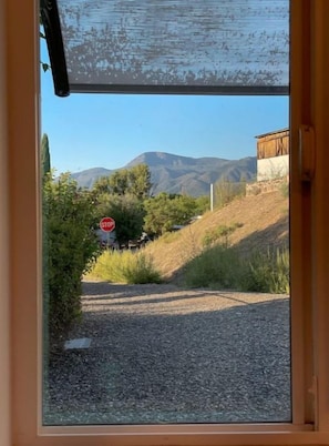 Vista a través de una ventana, con una señal de parada, un camino de grava y un edificio al fondo.