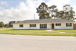 A single-story, white building with a grey roof, a front door, and a small porch. - Spacious, Remodeled Home in the Heart of Hammond (Hammond)