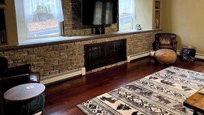 A living room with a stone fireplace, a television mounted above it, and a sign reading "Haines Falls". - Cozy Home With Fire Place 10 Mins From Hunter Mountain (Palenville)