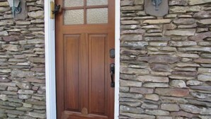 A wooden door with a glass panel and a stone wall with two wall-mounted lights. - Cozy Home With Fire Place 10 Mins From Hunter Mountain (Palenville)