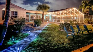 A house with a covered patio area, a pathway, and outdoor seating. - Ellie’s Landing 2 – Waterfront Gem w/ 2 Masters (Port Charlotte)