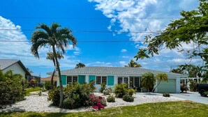 A residential house with a white exterior, green shutters, and a well-maintained lawn. - Ellie’s Landing 2 – Waterfront Gem w/ 2 Masters (Port Charlotte)