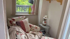 Una habitació acollidora amb un sofà, una taula petita i una finestra que dona a zona verda.