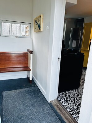A hallway with a wooden bench, a map on the wall, and a patterned carpet. - Adorable private cottage with lake views and access. (Dedham)
