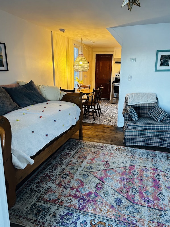 A cozy room with a bed, a sofa, a dining table, and a kitchen area. - Adorable private cottage with lake views and access. (Dedham)