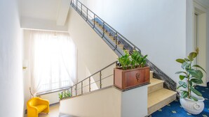 A staircase with a wooden handrail and a potted plant on the landing.