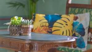 A wooden table with woven baskets containing succulents, a colorful pillow, and a chair with a green and blue floral pattern.