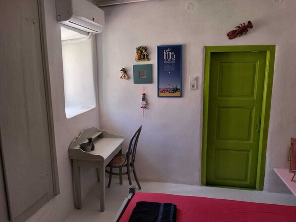 A room with a desk, chair, bed, and a green door. - Cycladic-style house, pool, 10 minutes to the beach (Galissas)