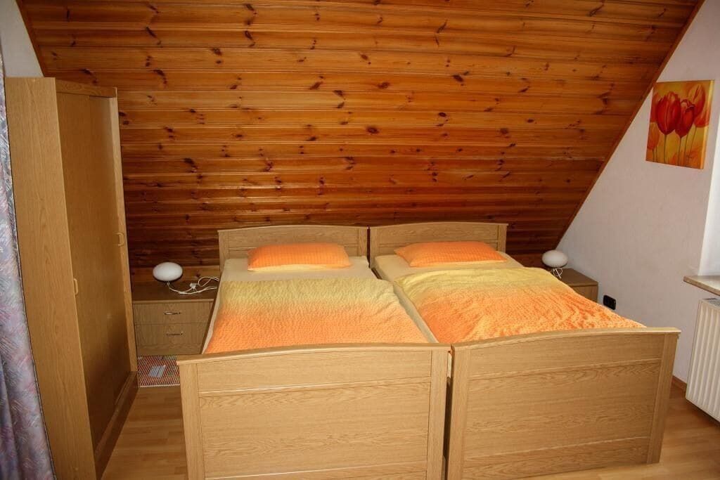 A bedroom with two wooden beds, a wardrobe, and a radiator.