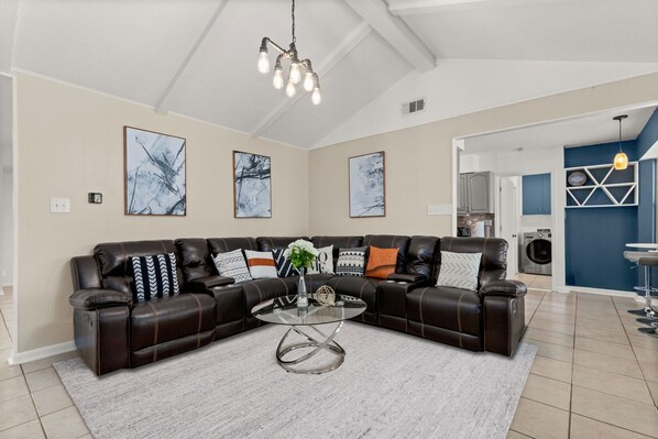 A modern living room with a sectional sofa, a glass coffee table, and abstract wall art.