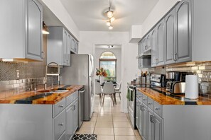 A modern kitchen with grey cabinets, a wooden countertop, and stainless steel appliances.
