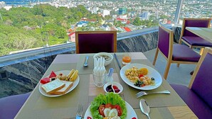 Una mesa de comedor con comida y vista a un paisaje urbano.