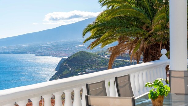 A balcony with a glass table, chairs, and a potted plant. - Family villa with private heated pool and ocean views (Tabaiba)