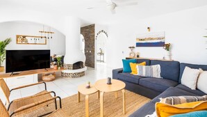 A modern living room with a fireplace, sofa, TV, and a dining area. - Family villa with private heated pool and ocean views (Tabaiba)