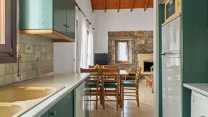 Una cocina con armarios color turquesa, techo de madera, pared de piedra y un comedor con sillas y mesa de madera.