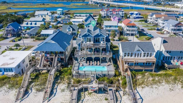 A coastal residential area with multiple houses, a large central building with a swimming pool, and a beach in the foreground. - Tipsy Turtle North- Oceanfront Oasis - Pool - Dog Friendly (Surf City)