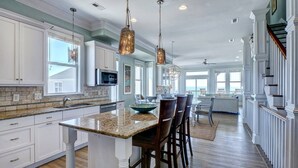A spacious kitchen with granite countertops, white cabinetry, and pendant lighting. - Tipsy Turtle North- Oceanfront Oasis - Pool - Dog Friendly (Surf City)