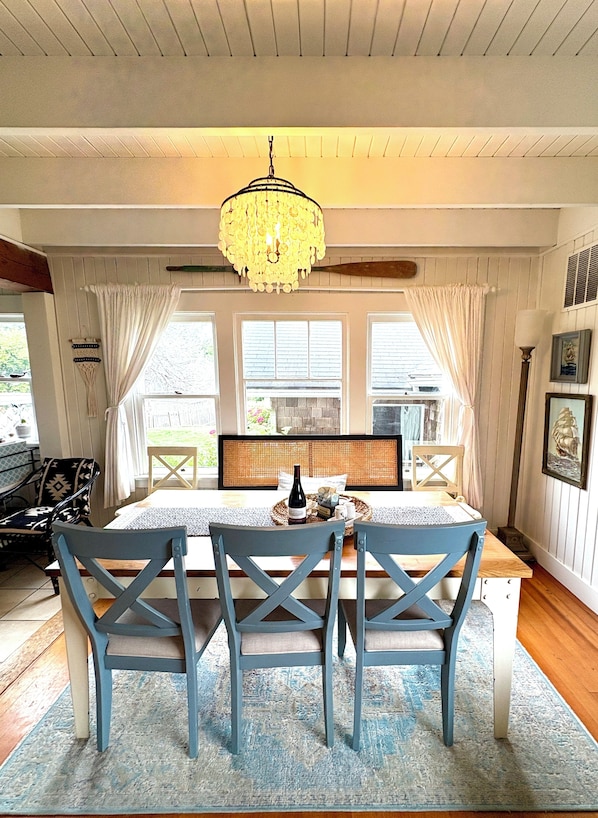 A dining area with a table, chairs, a chandelier, and a view of the outdoors.