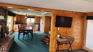 L’intérieur de ce chalet rustique et chaleureux comprend un coin repas, une cuisine et un téléviseur à écran plat fixé au mur.