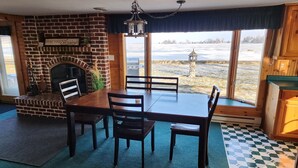 Un coin repas avec une cheminée en briques, une table en bois et des chaises.