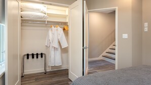 Ein Schlafzimmer mit einem Bett, einem Kleiderschrank mit Kleidung und einer Treppe.