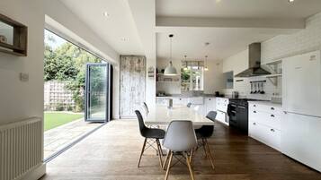 A modern kitchen with white cabinetry, a central island, and a dining area with a glass door leading to a garden.