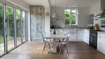 A modern kitchen with large windows, a dining table, and white cabinetry.