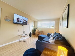 Relax in this stylish living room with a flat-screen TV, dark sofa, and a cozy coffee table.