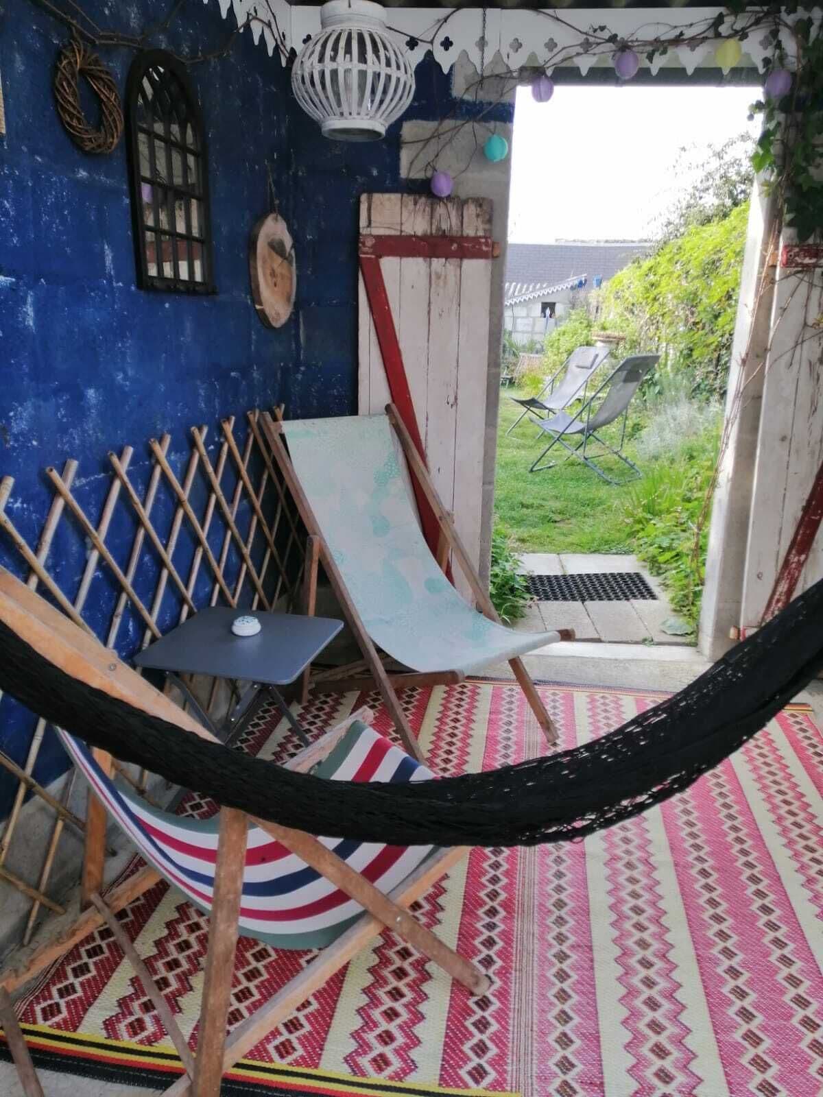 Een hangmat, een stoel en een klein tafeltje in een kamer met een patroon vloer en een blauwe muur.