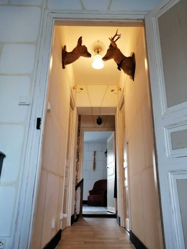 A hallway with a wooden floor, white walls, and a ceiling light fixture.